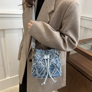 Borsa a secchiello in denim trapuntato con coulisse, abbinata a un blazer di lana marrone