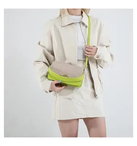 Detail of woven straw flap and light green leather shoulder bag with gold metal buckle