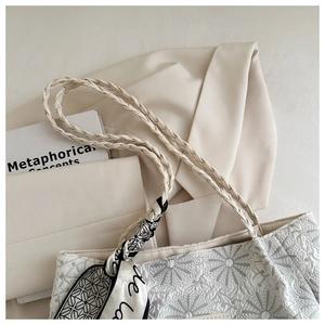 Close-up of floral embroidery texture and braided strap on cream tote bag