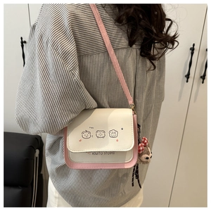Detail of pink and white crossbody bag with cute cartoon prints and a plush bear charm
