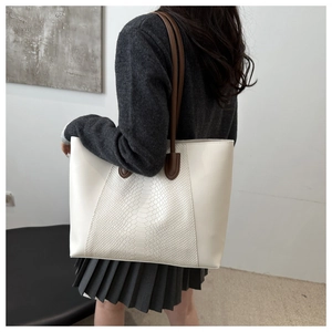 Detail of minimalist cream tote bag featuring textured faux crocodile skin panel