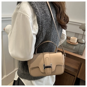 Detail of beige leather handbag with silver clasp shown on a model's shoulder