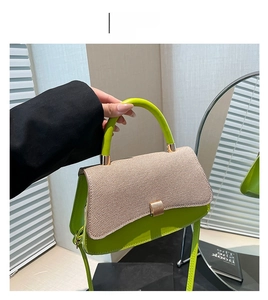 Detail of green leather baguette bag with beige woven flap and golden buckle hardware