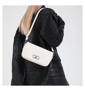 Close-up of a white leather flap crossbody bag with a silver metal clasp on a model