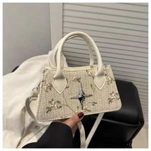 Ricamo dettagliato di fiori rosa su una mini borsa a mano intrecciata color crema