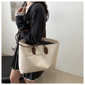 Detail of minimalist cream tote bag featuring snakeskin texture and brown shoulder straps