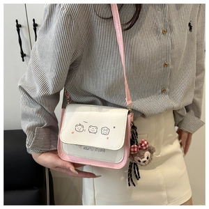 Detail shot of a pink and white crossbody bag with cartoon bear and plush charm on a model