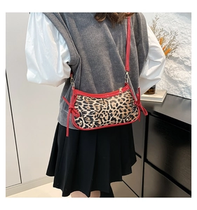 Detail of leopard print underarm bag with red leather trim and metal rivets