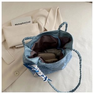 Top-down view of blue quilted tote bag with woven handles and decorative scarf detail