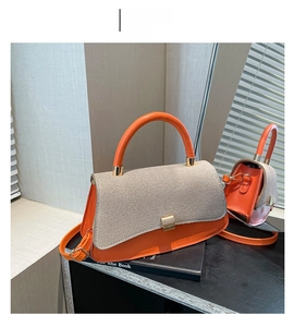 Detail of orange leather and woven fabric shoulder bag with golden buckle on a mirror
