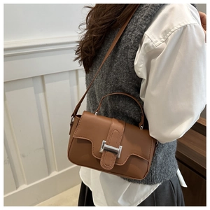 Detailed side view of brown leather square shoulder bag with silver metallic buckle clasp