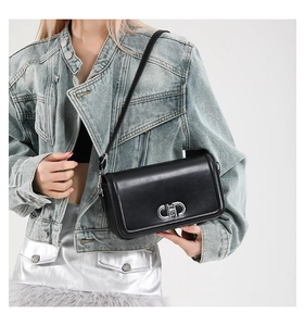 Close-up of elegant black leather square handbag featuring silver interlocking metal buckle
