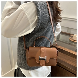 Detail of a brown leather crossbody bag with silver metallic buckle and shoulder strap