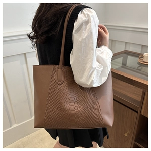 Detail of brown tote bag featuring snakeskin texture and elegant patchwork design