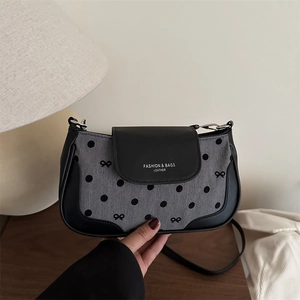 Sac sous l'aisselle à pois en denim gris et cuir noir sur surface en bois