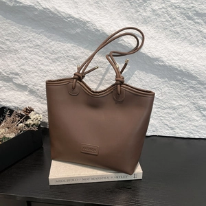 Minimalist dark brown tote bag in matte leather featuring embossed fashion logo details