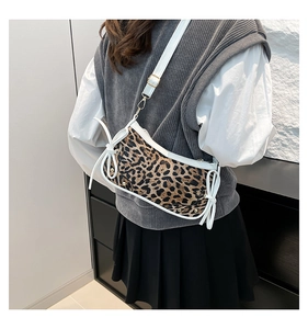 Detailed view of leopard print crossbody bag with white ribbon bows and golden buckles