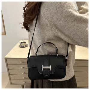 Detail of black matte shoulder bag with silver H-buckle worn by a model in casual style