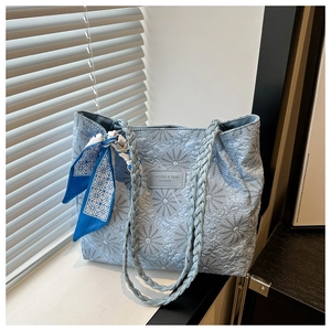 Detail of light blue nylon tote bag with 3D floral texture and woven scarf handle