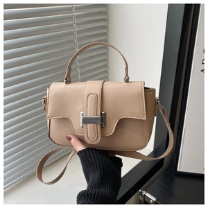 Detailed close-up of beige crossbody bag with rectangular metal buckle and smooth leather