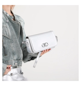 Detail of silver metallic square crossbody bag with dual-ring clasp on a fashion model