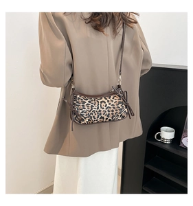 Detailed view of leopard print crossbody bag with brown leather trim and side bow knots