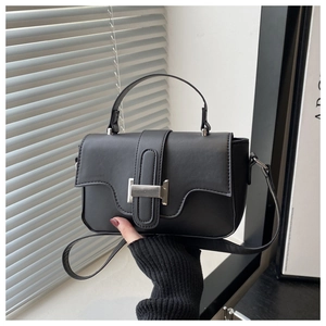 Detail of black crossbody bag featuring a silver H-shaped buckle and matte leather texture