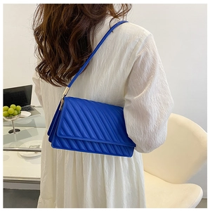Détail du sac à bandoulière matelassé bleu vif avec coutures fines et ferrures dorées