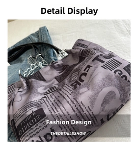 Detail of light purple newspaper print tote bag with silver chain and black shoulder strap