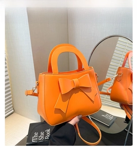 Dettaglio della borsa arancione vivace con fiocco decorativo e finiture in metallo dorato