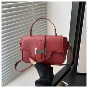 Close-up of a deep red matte leather bag featuring a sleek silver metal buckle detail