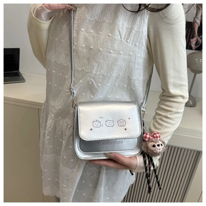 Detail of silver crossbody bag with cute animal illustrations and plush bear charm