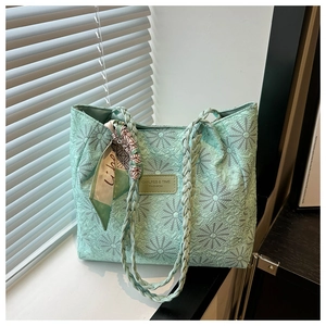 Detail of mint green tote bag with daisy jacquard texture and braided handle