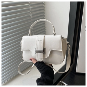 Close-up of cream square crossbody bag with silver metal buckle and refined stitching