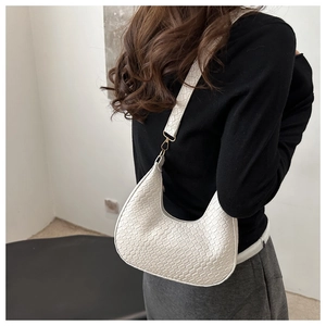 Detail of white crescent shoulder bag featuring woven texture and golden metal buckle