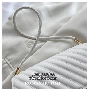 Détail de la texture cuir matelassé blanc et ferrures en métal doré sur le sac à main