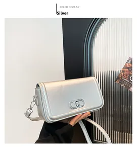 Close-up of silver crossbody bag with metallic lock and adjustable shoulder strap