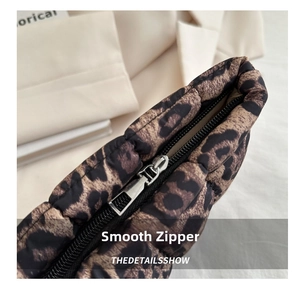 Close-up of smooth metal zipper and leopard print quilted texture on the luxury bag