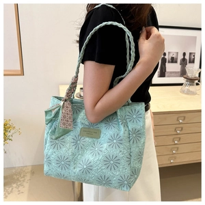 Detail of mint green daisy tote bag with woven handles and silk scarf on a side view