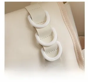 Makro-Detail der beigefarbenen Kunstledertasche mit drei D-Ringen für Anhänger und Zubehör
