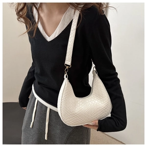 Detailed texture of white crocodile-embossed crescent bag with golden metal hardware