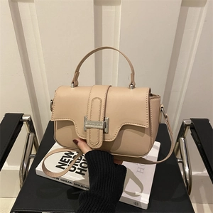 Minimalist beige crossbody bag with silver buckle and top handle in a modern urban style