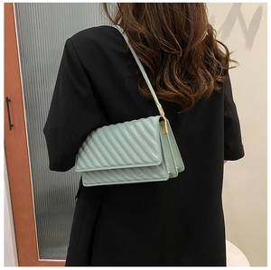 Vue détaillée du sac à bandoulière matelassé vert menthe porté sur un blazer noir