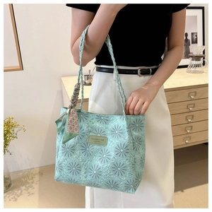 Detail of light green tote bag featuring daisy embroidery and woven rope handles