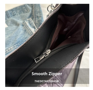 Detailed view of the smooth silver zipper and purple textured fabric on the large tote bag