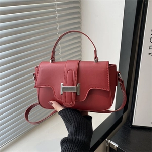 Vintage red leather shoulder bag with top handle and silver buckle in minimalist style