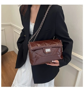 Close-up of brown quilted shoulder bag with silver chain strap and metal swivel lock