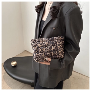 Detail of a leopard print quilted clutch bag held by a model in a luxury setting