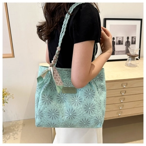 Detail of mint green quilted tote bag with floral patterns and chic scarf on handle