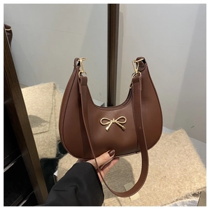 Macro detail of brown faux leather crescent bag with golden bow metallic buckle